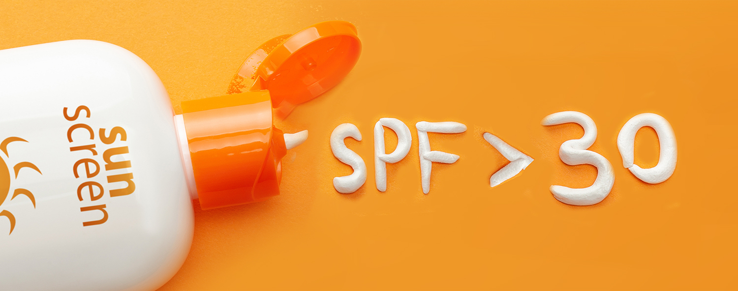 Sunscreen on orange background. Plastic bottle of sun protection and white cream in the form of question mark and numbers SPF. How to choose a sunscreen